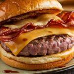 Cheesy bacon burger with crispy bacon, melted cheese, and a juicy patty on a toasted bun.