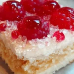 A slice of Raspberry Swirl Coconut Snowball Cake with raspberry swirl and shredded coconut topping on a white plate.