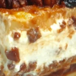 A delicious slice of Pecan Pie Lasagna with layers of graham cracker crust, cream cheese filling, pecan pie topping, and caramel drizzle.